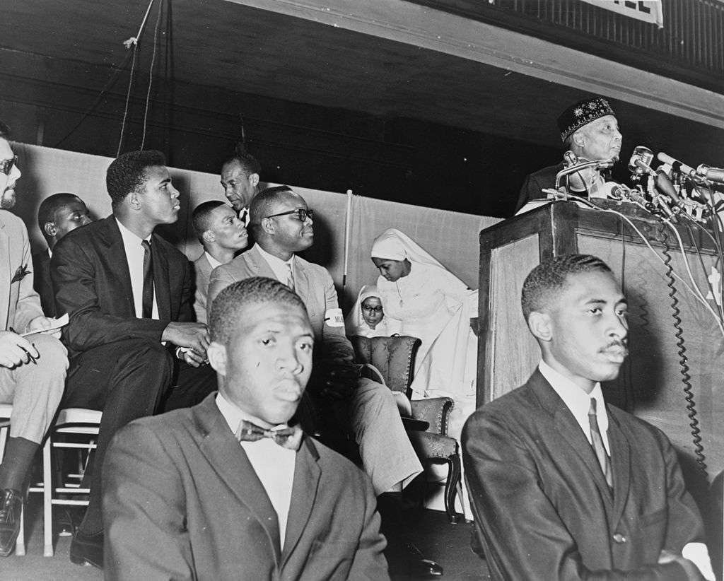  Ali (seen in background) at an address by Elijah Muhammad in 1964