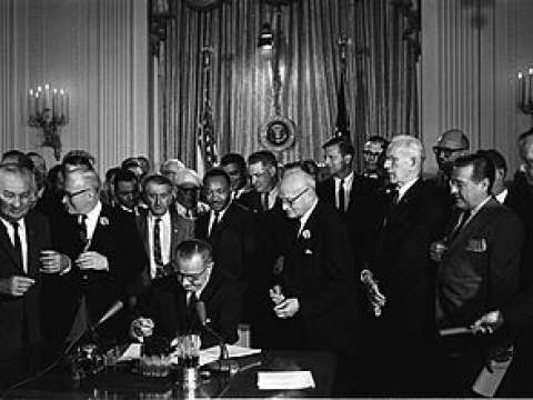 King stands behind President Johnson as he signs the Civil Rights Act of 1964.