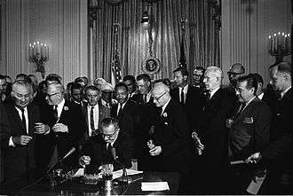 King stands behind President Johnson as he signs the Civil Rights Act of 1964.