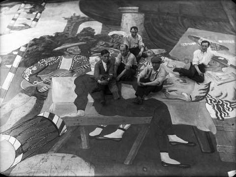 Pablo Picasso and scene painters sitting on the front cloth for Léonide Massine's ballet Parade, staged by Sergei Diaghilev's Ballets Russes at the Théâtre du Châtelet, Paris, 1917