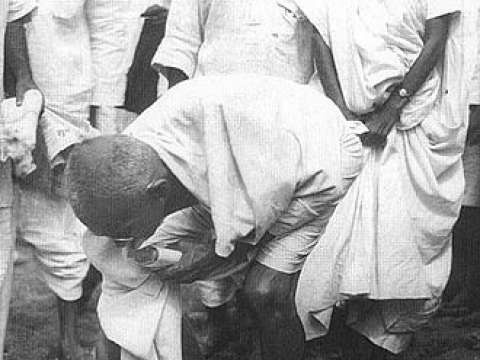 Gandhi picking salt during Salt Satyagraha to defy colonial law giving salt collection monopoly to the British.