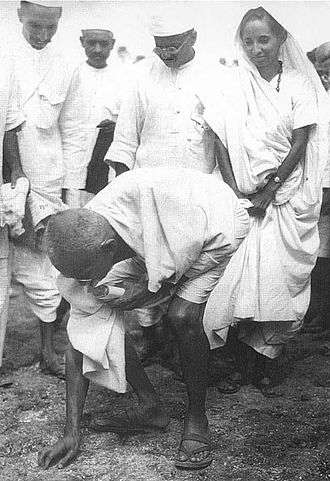 Gandhi picking salt during Salt Satyagraha to defy colonial law giving salt collection monopoly to the British.