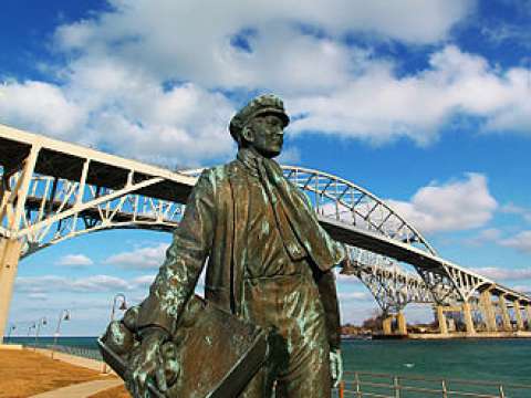 Statue of young Thomas Edison by the railroad tracks in Port Huron, Michigan. The Blue Water Bridge can be seen in the background.