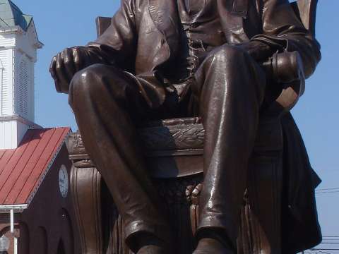 Abraham Lincoln, a 1909 bronze statue by Adolph Weinman, sits before a historic church in Hodgenville, Kentucky.