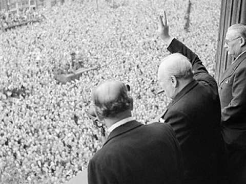 Churchill waving the Victory sign to the crowd in Whitehall on the day he broadcast to the nation that the war with Germany had been won, 8 May 1945. Ernest Bevin stands to his right.