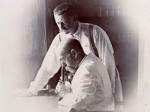 Koch (on the microscope) and his colleague Richard Friedrich Johannes Pfeiffer (standing) investigating cholera outbreak in Bombay, India.