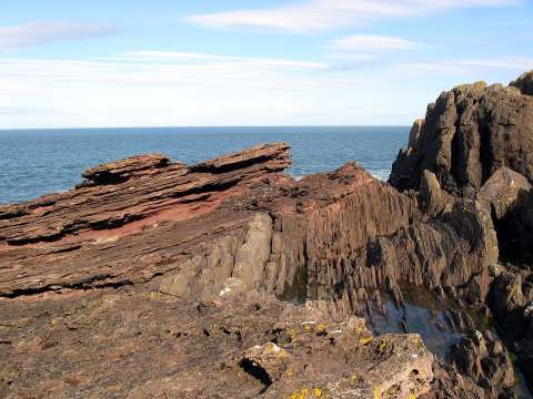 An eroded outcrop at Siccar Point showing sloping red sandstone above vertical greywacke was sketched by Sir James Hall in 1788.